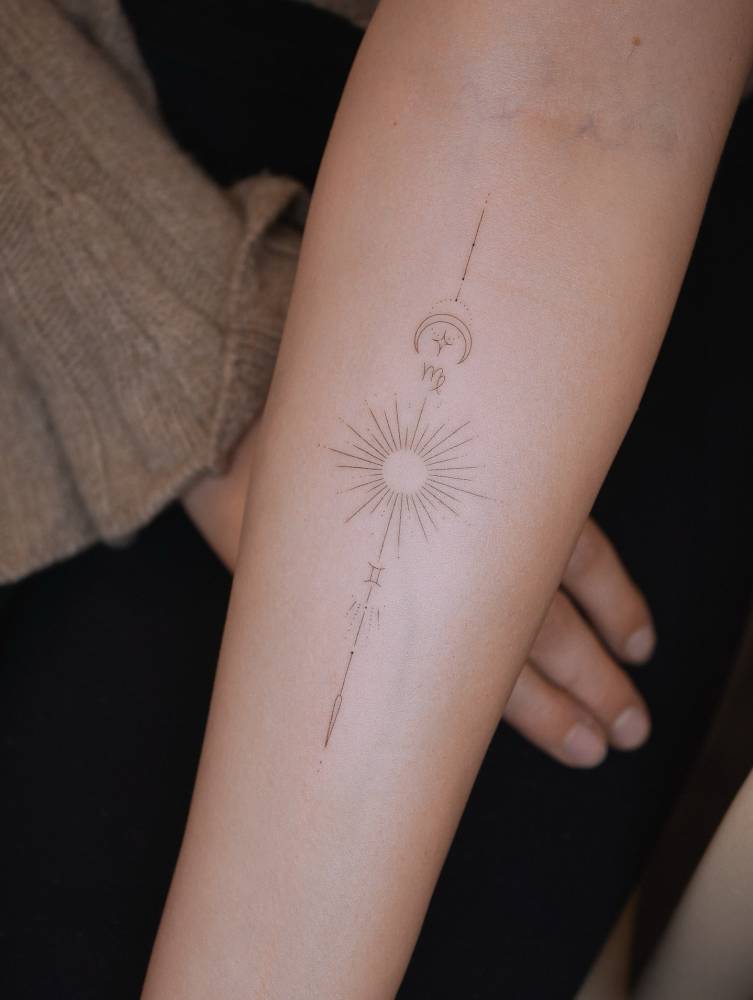 Sun, moon and Zodiac symbols tattooed on the inner forearm.
