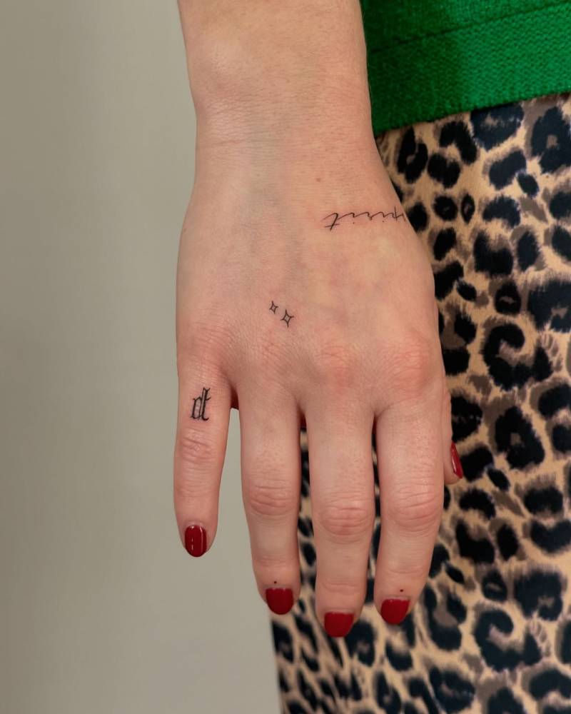 Letter "D" in gothic font and tiny stars tattooed on the hand.