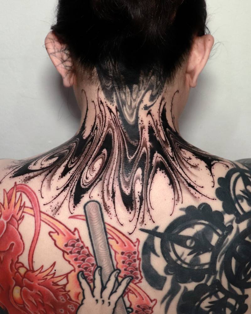 Abstract tattoo in blackwork style located on the back of the neck.