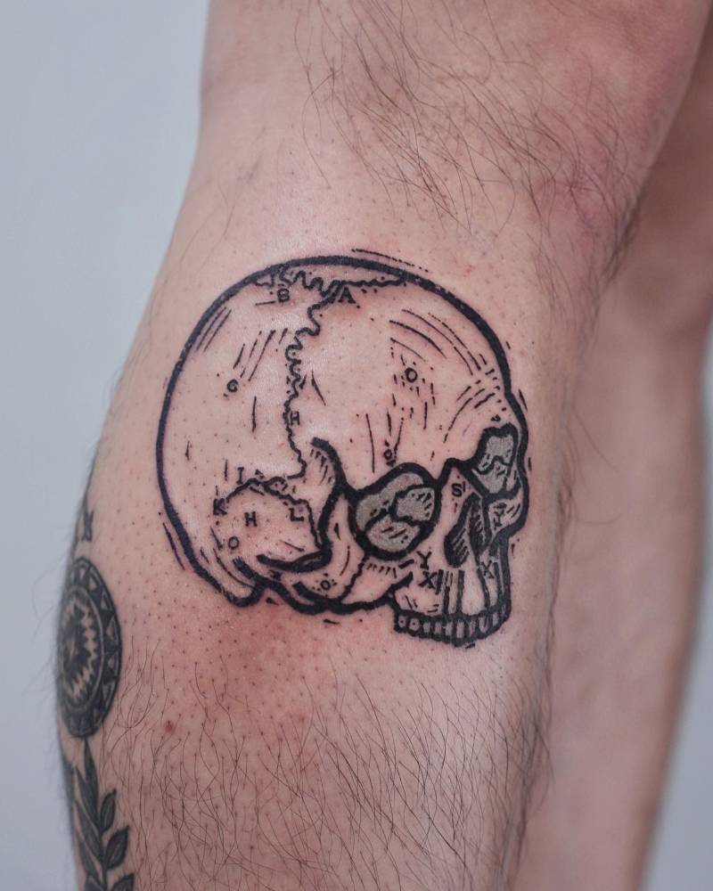 Engraving style skull tattoo placed on the shin.