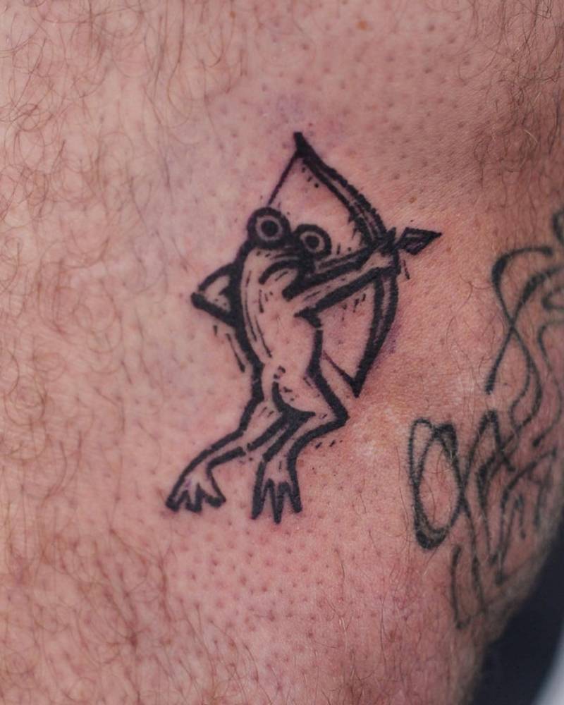 Archer frog tattoo located on the knee, blackwork style.