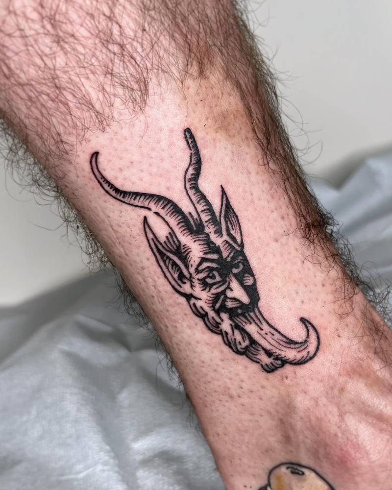 Devil portrait tattoo placed on the ankle, done in engraving style.