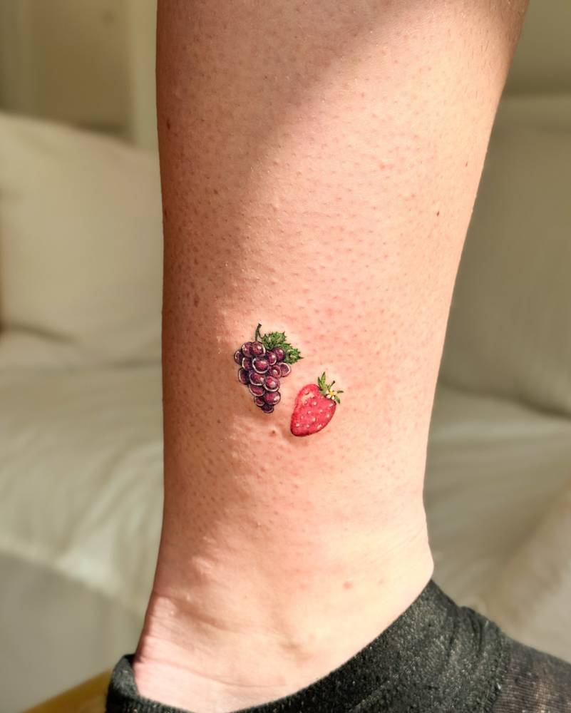 Illustrative style strawberry and grapes tattoo located on the ankle.