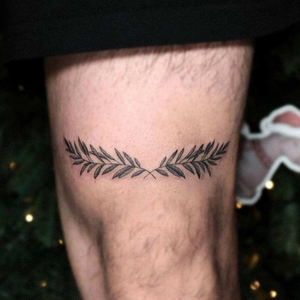Laurel wreath tattoo located on the thigh.