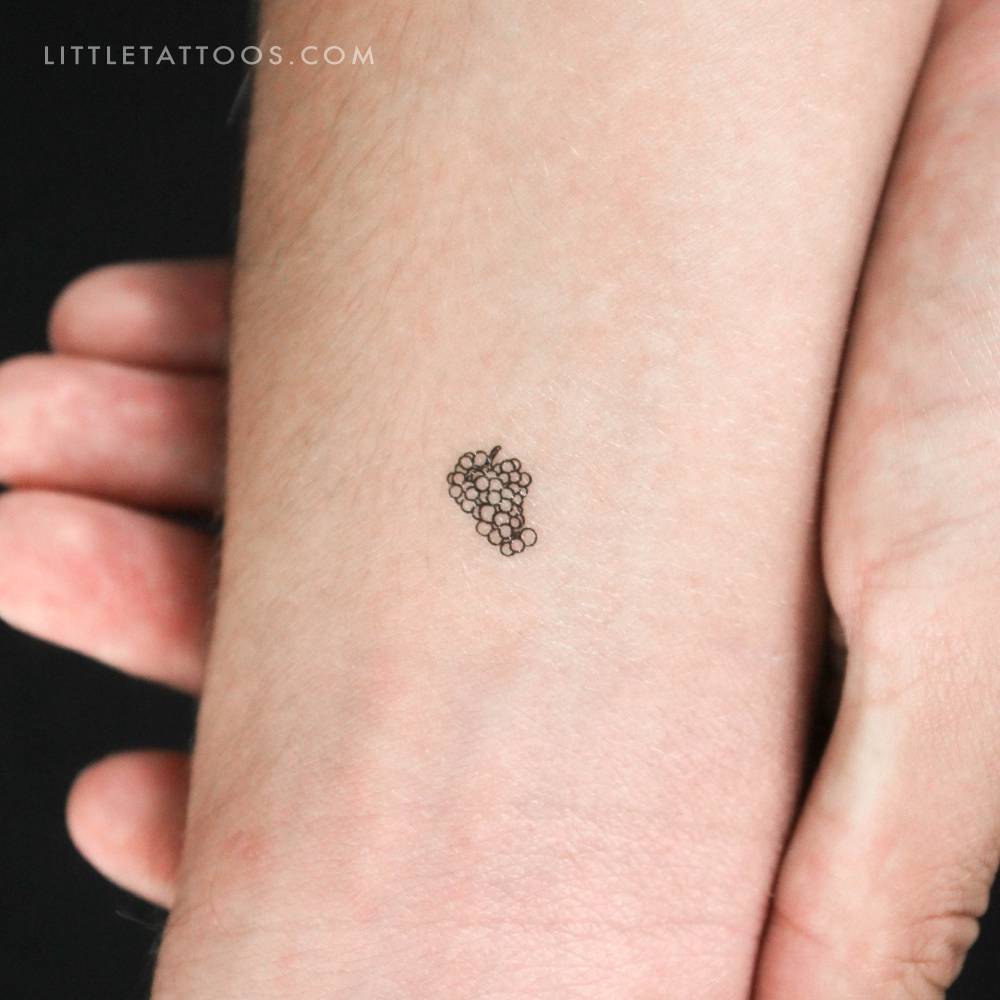 Tiny fine line style grapes temporary tattoo located on the wrist.
