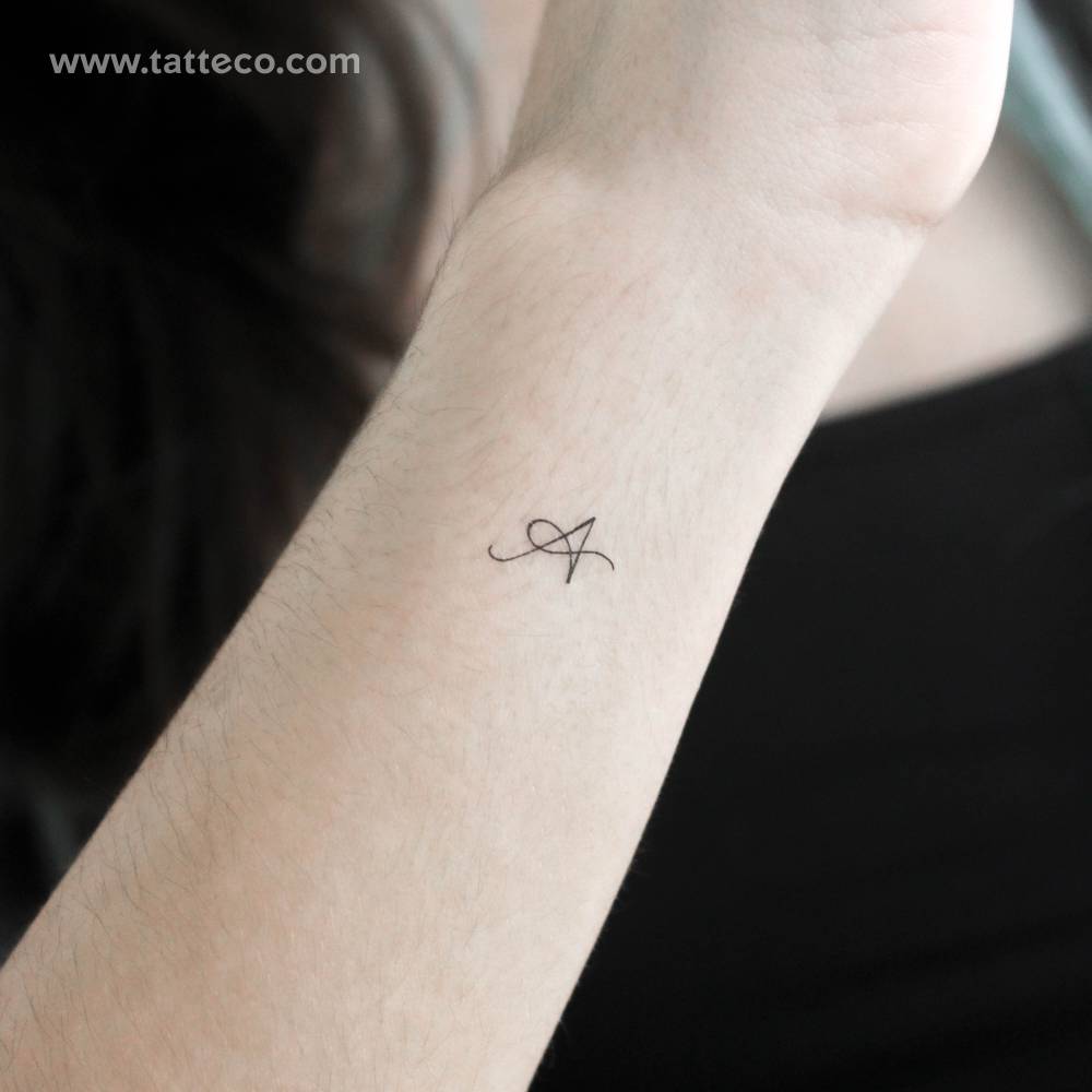 Script letter "A" temporary tattoo located on the wrist.