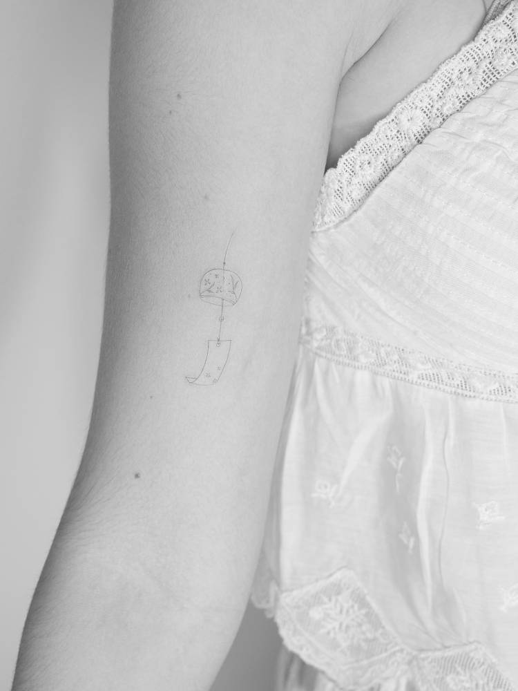 Fine line style Chinese lantern tattoo located on the bicep.