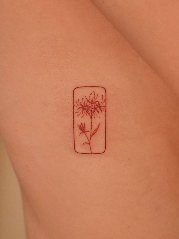 Red spider lily tattoo in red ink located on the rib.