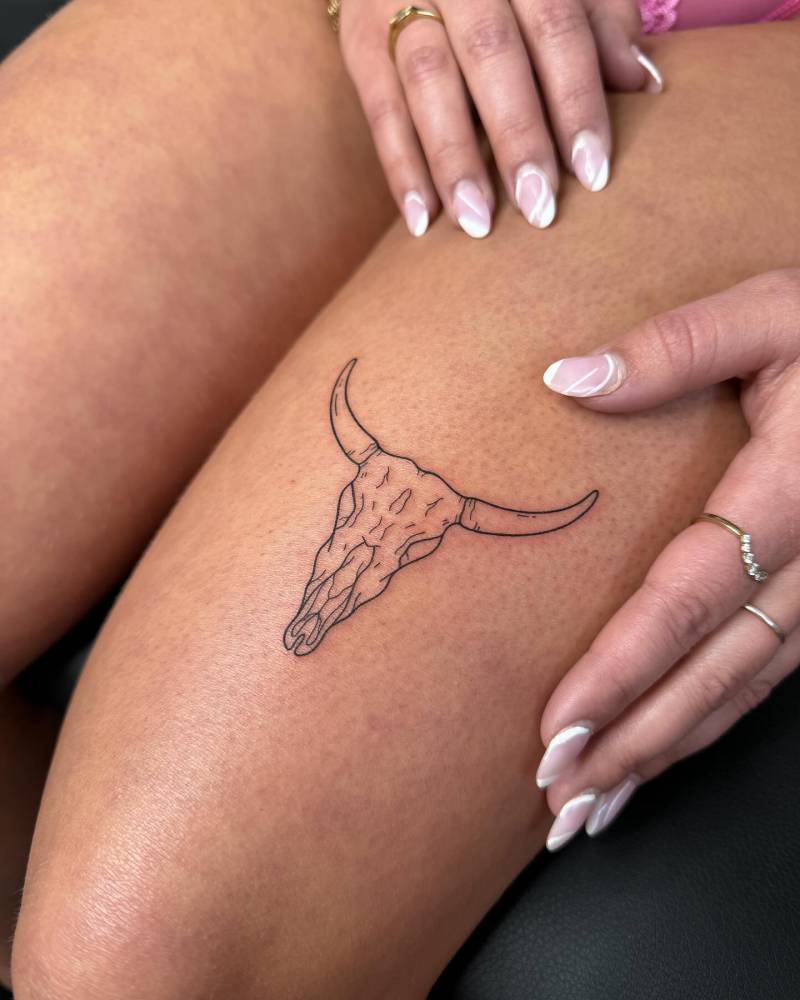 Bull skull tattoo located on the thigh, fine line style.