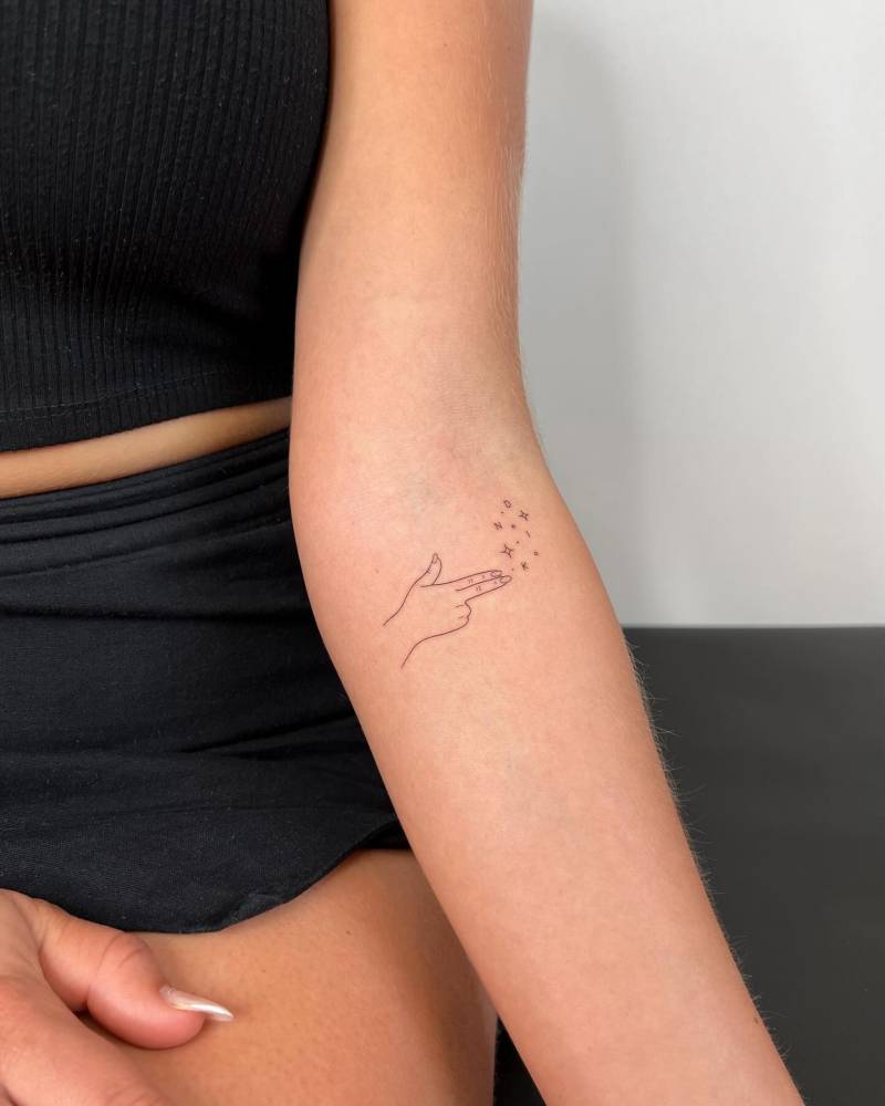 Little hand and stars tattoo in fine line style placed on the inner forearm.