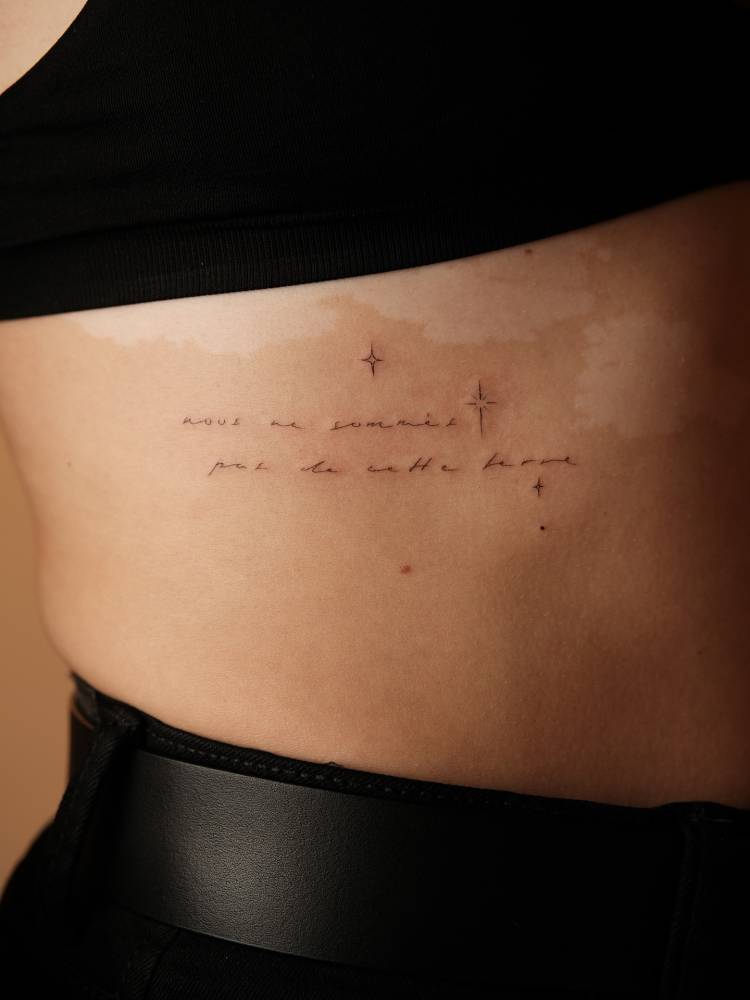 French quote and sparkling stars tattoo located on the rib.