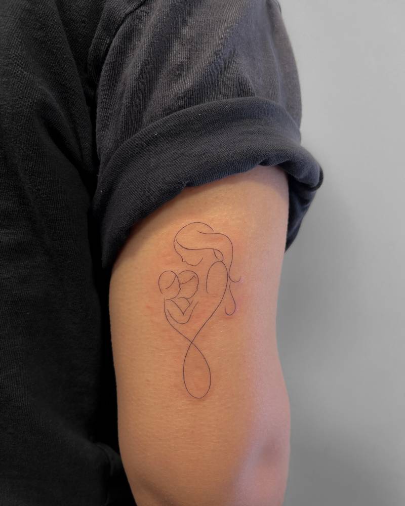 Mother and daughters symbol tattooed on the tricep, fine line style.