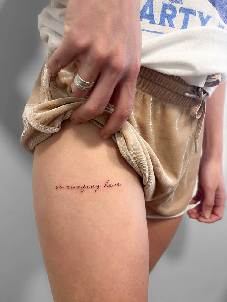 "So amazing here" lettering tattoo placed on the thigh.