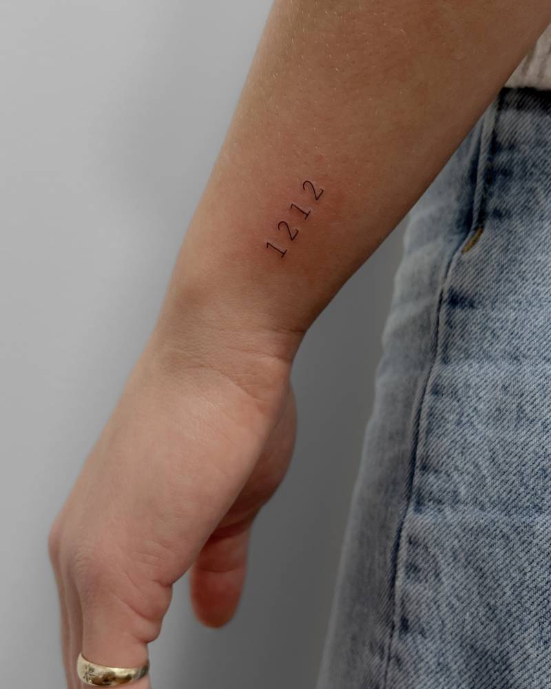 Typewriter font "1212" lettering tattoo placed on the wrist.