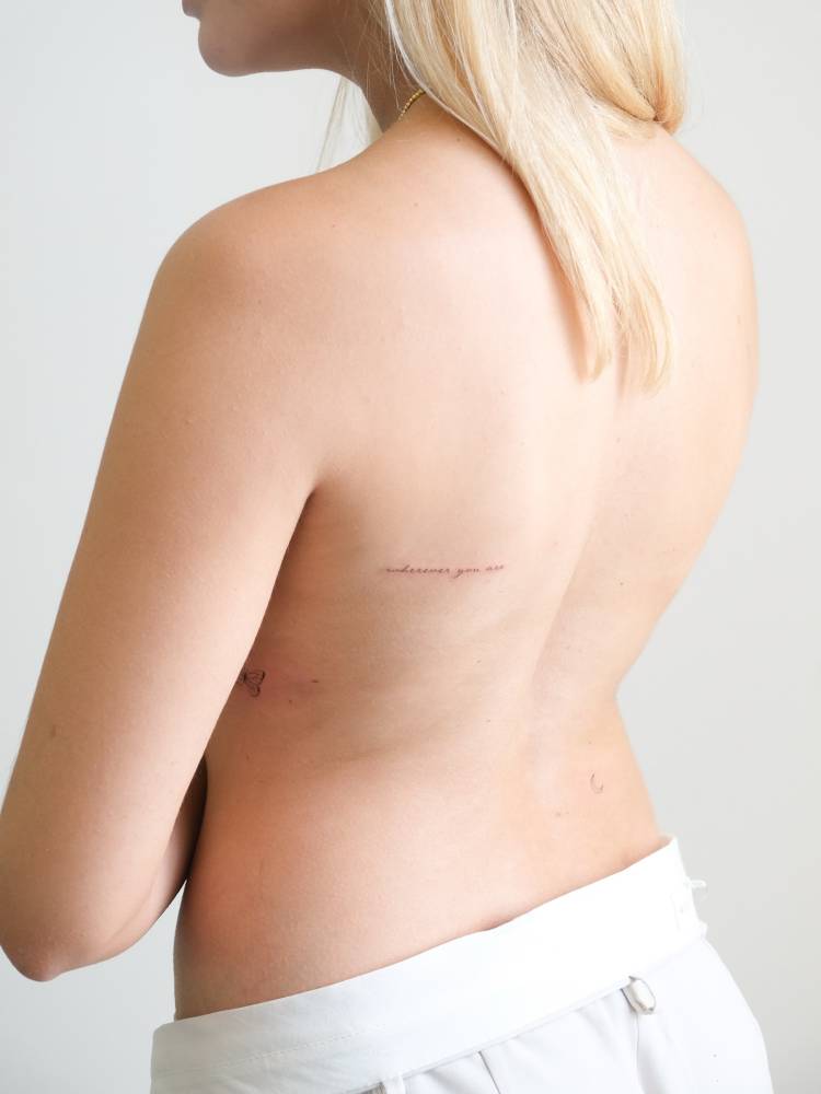 Handwritten font "wherever you are" lettering tattoo located on the shoulder blade.