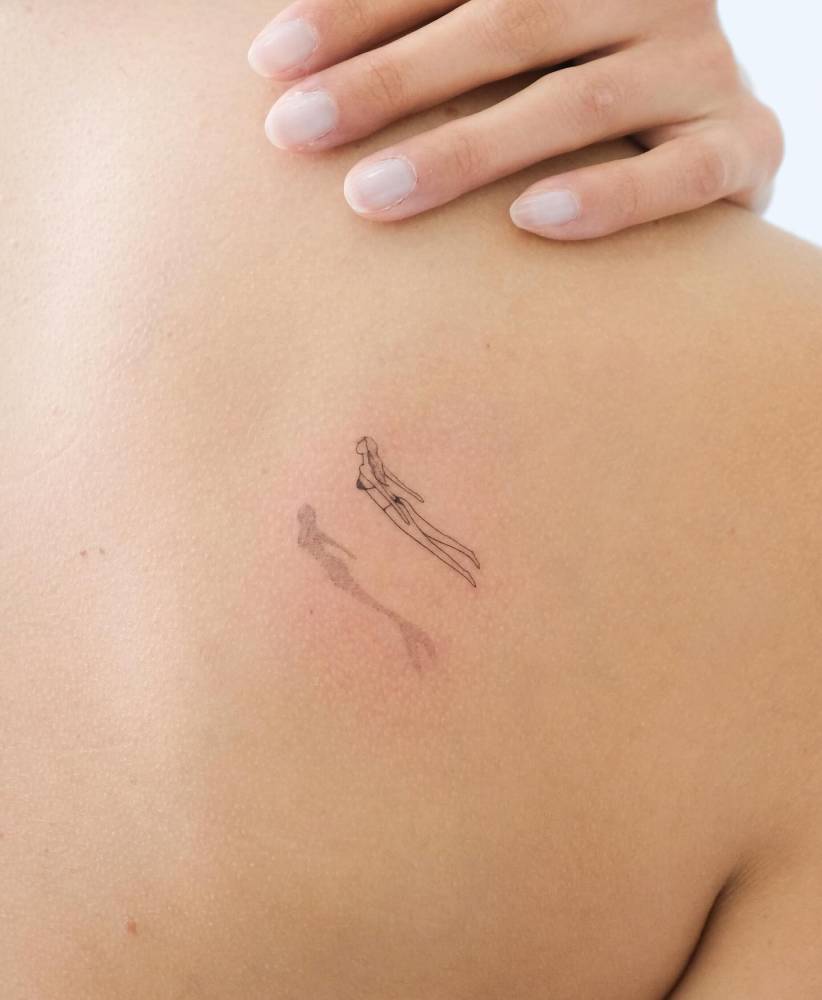 Single needle swimmer tattoo located on the shoulder blade.