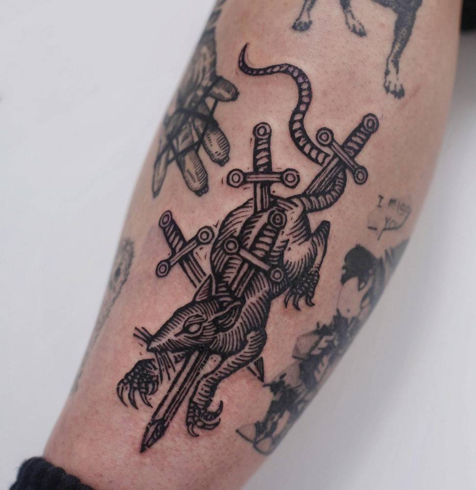 Rat and swords in engraving style tattooed on the shin.