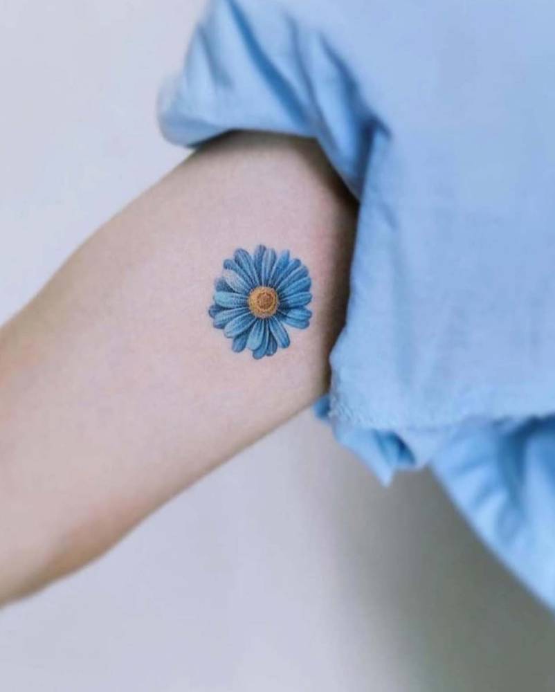 Daisy tattoo in micro-realistic style located on the inner arm.