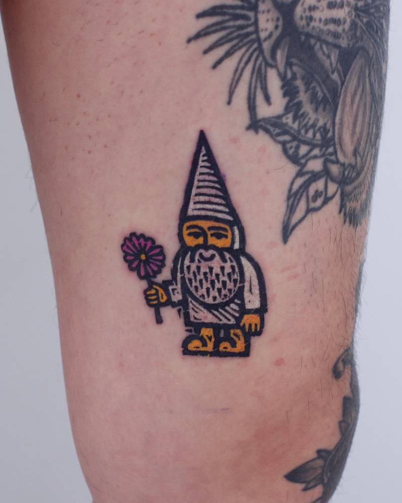 Gnome holding a flower tattooed on the thigh, pop art style.