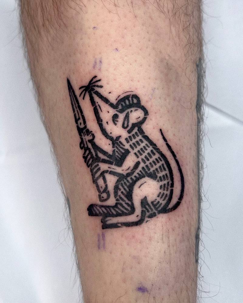 Rat holding a knife tattooed on the shin, done in blackwork style.