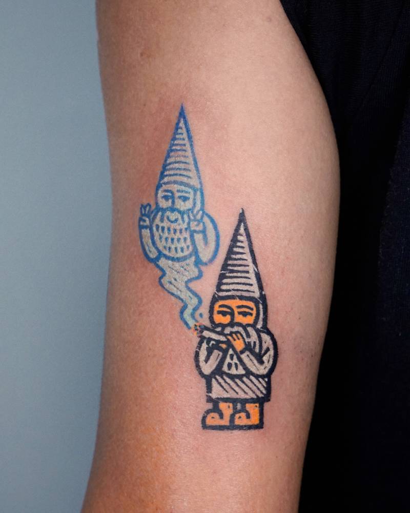 Smoking gnome tattoo located on the tricep.