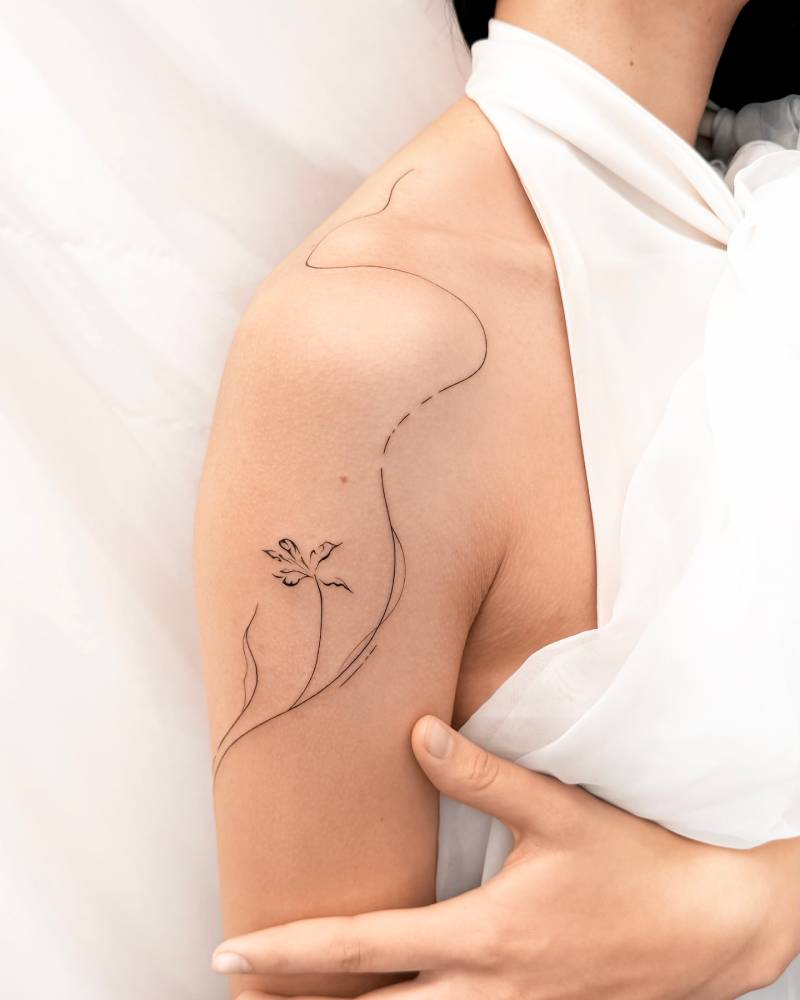 Line art style flower tattoo located on the upper arm and shoulder.