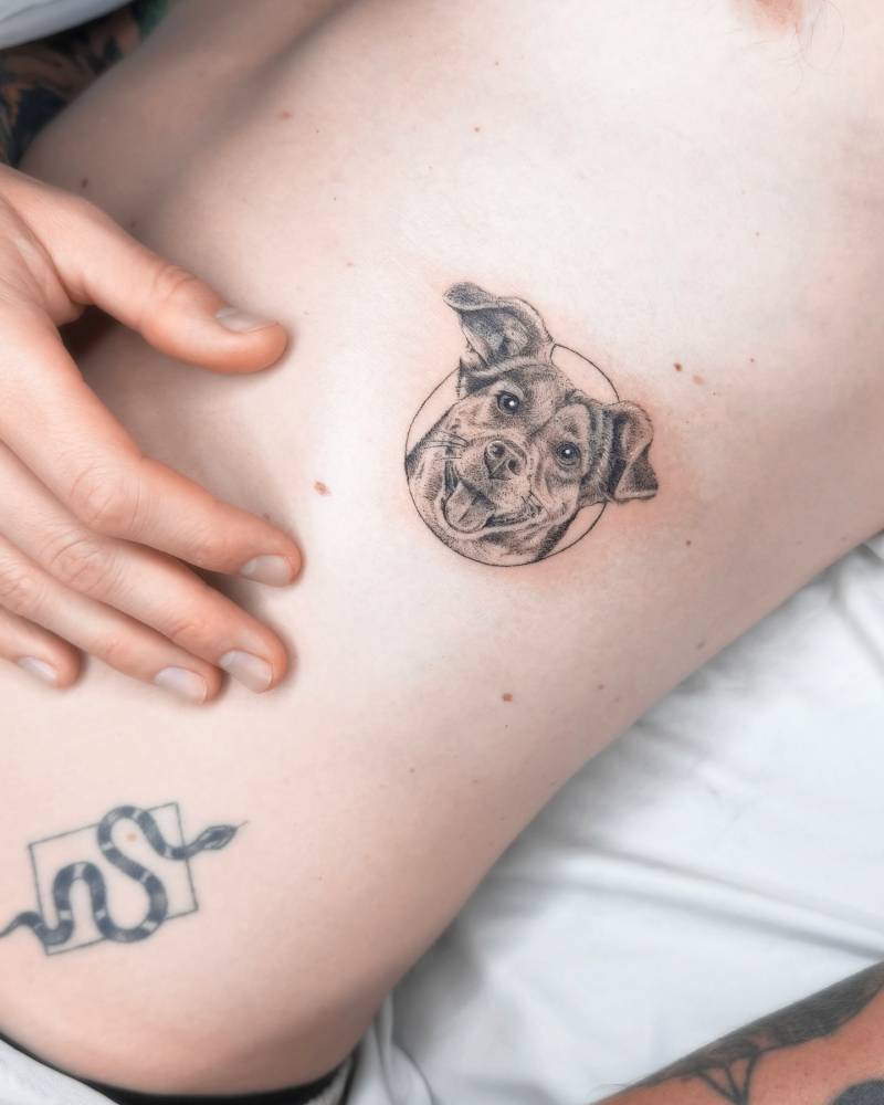 Micro-realistic dog portrait tattoo located on the rib.
