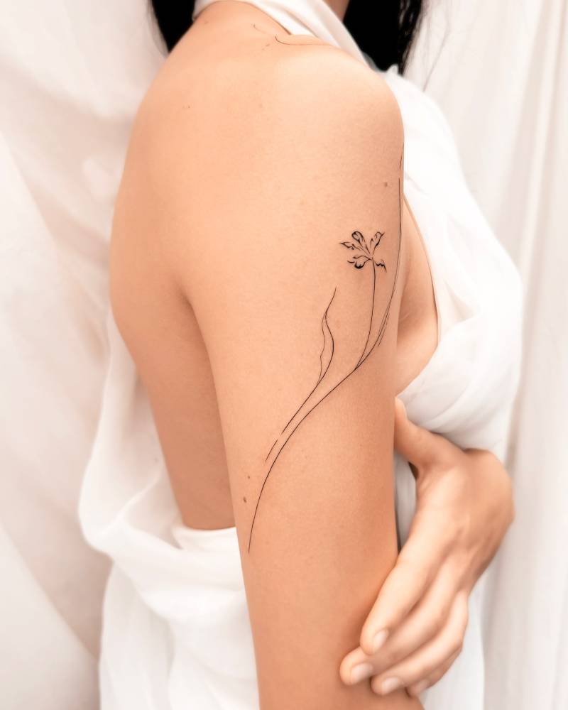 Flower tattoo in line art style placed on the upper arm.
