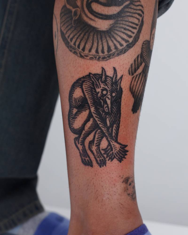 Engraving style Krampus tattoo located on the shin.