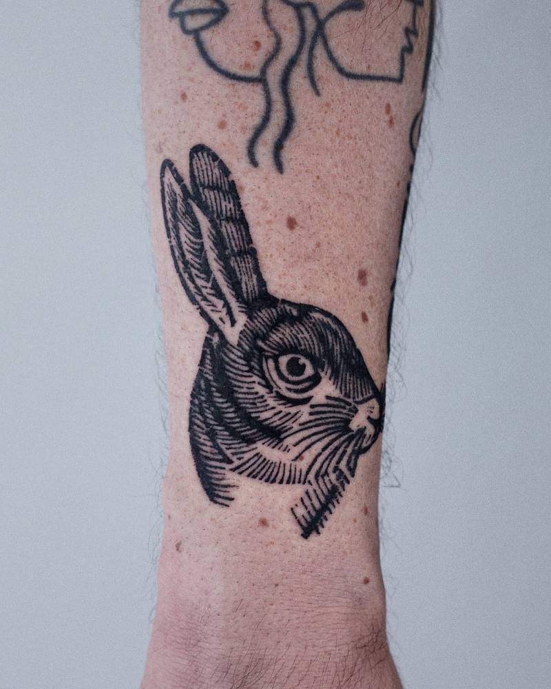 Engraving style hare portrait tattoo located on the shin.