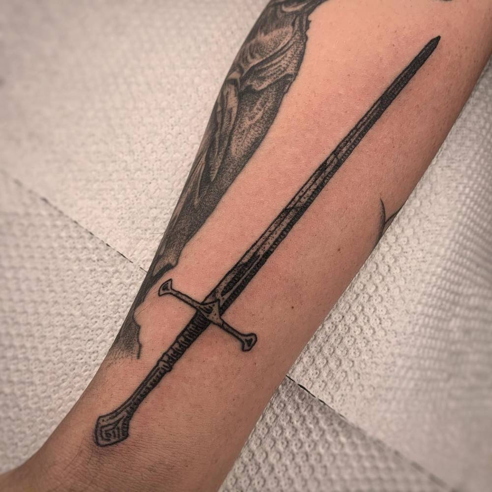 Blackwork style sword tattoo located on the inner forearm.