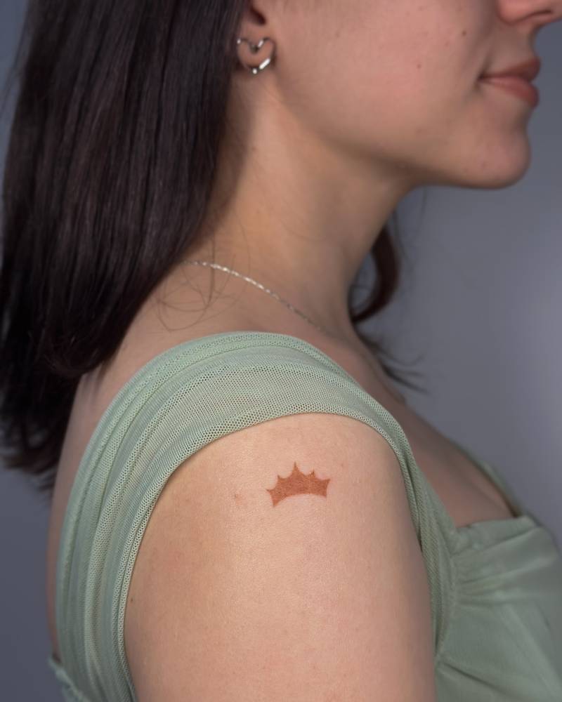 Illustrative style crown tattoo located on the shoulder.