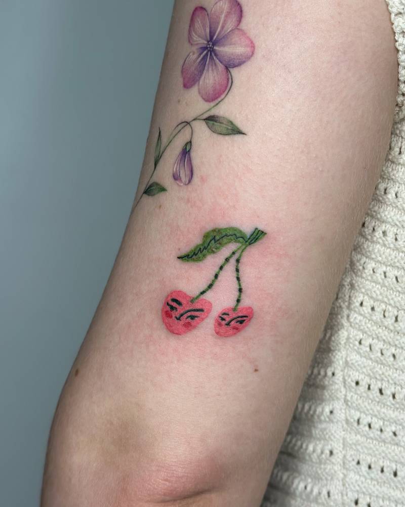 Little cherries tattoo in illustrative style placed on the tricep.