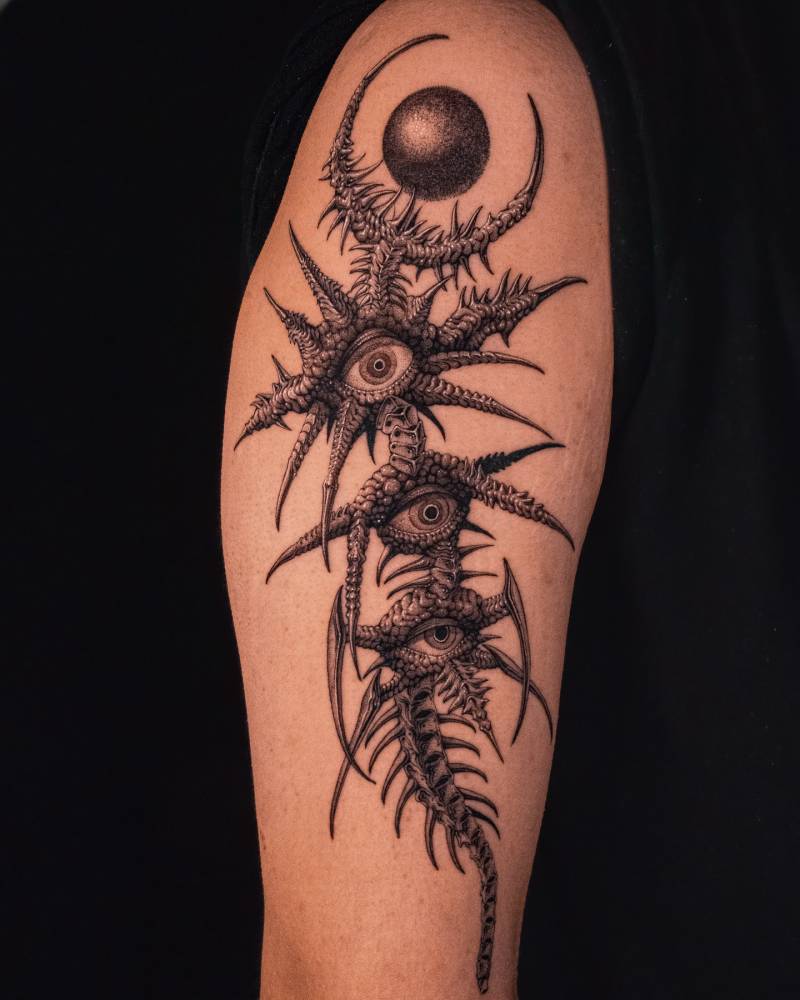 Thorns and eyes tattoo located on the upper arm in illustrative style.