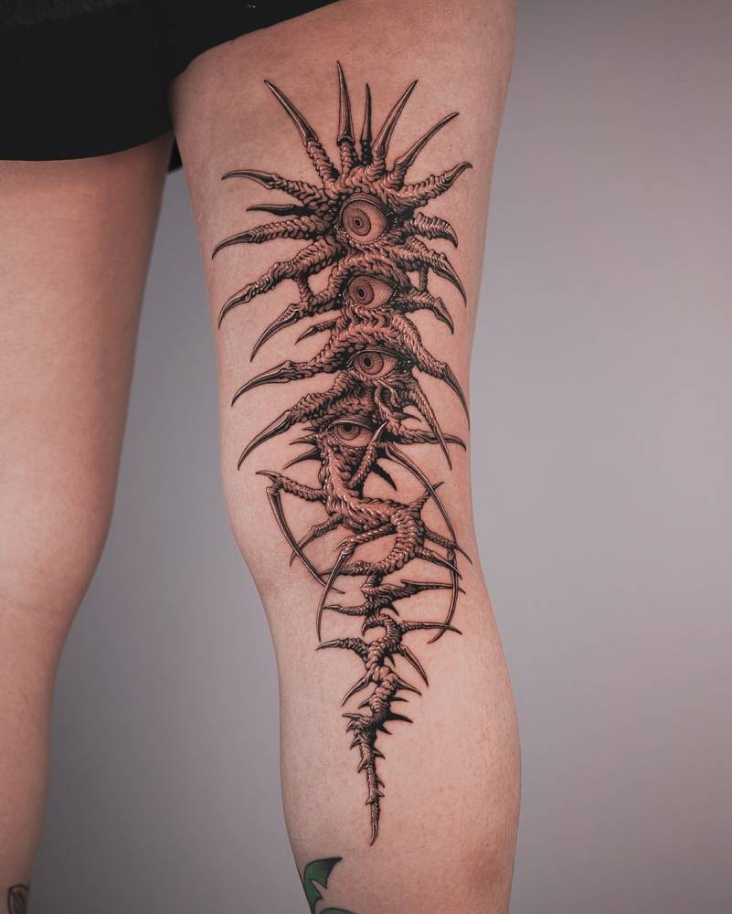 Illustrative style eyes and thorns tattoo located on the leg.