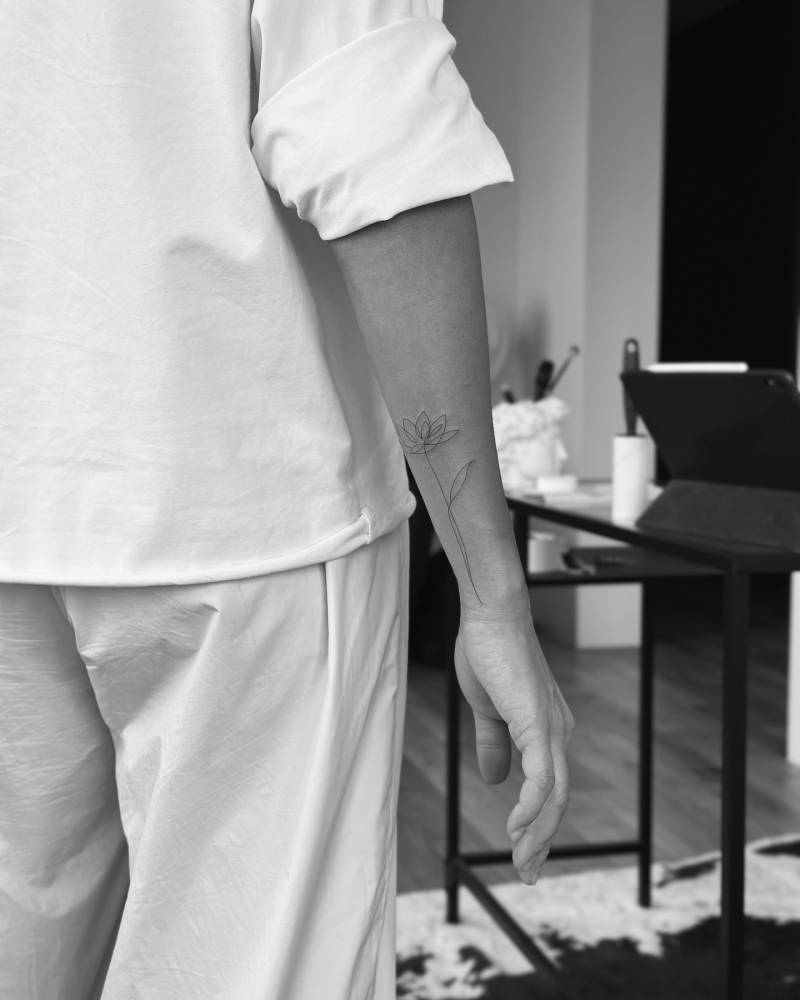 Lotus flower tattoo in fine line style located on the wrist.