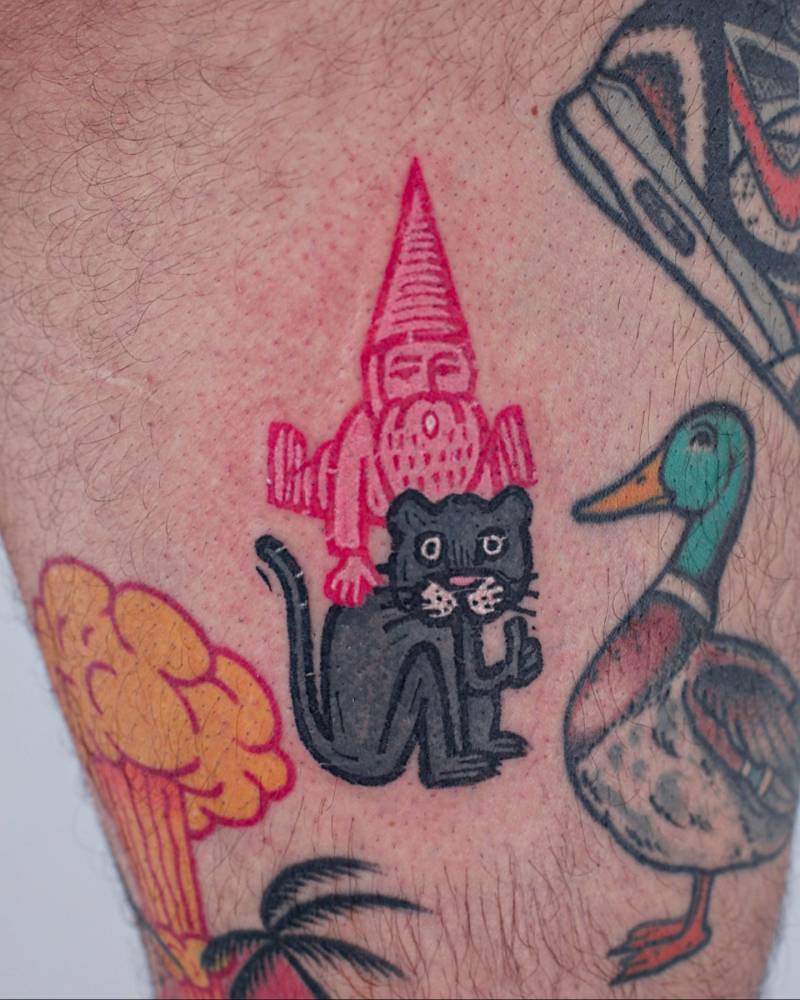 Gnome and cat tattoo in pop art style located on the thigh.
