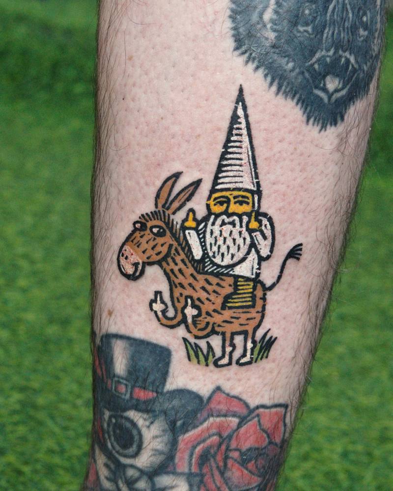 Gnome riding a donkey tattooed on the calf.