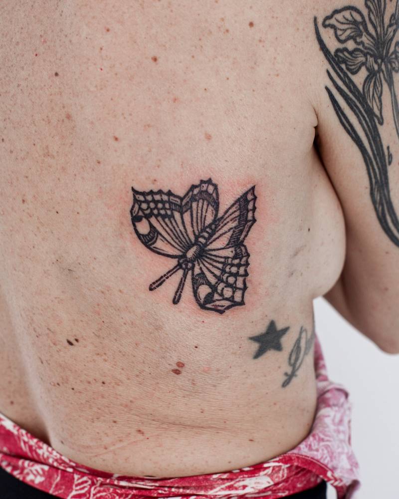 Engraving style butterfly tattoo placed on the back.