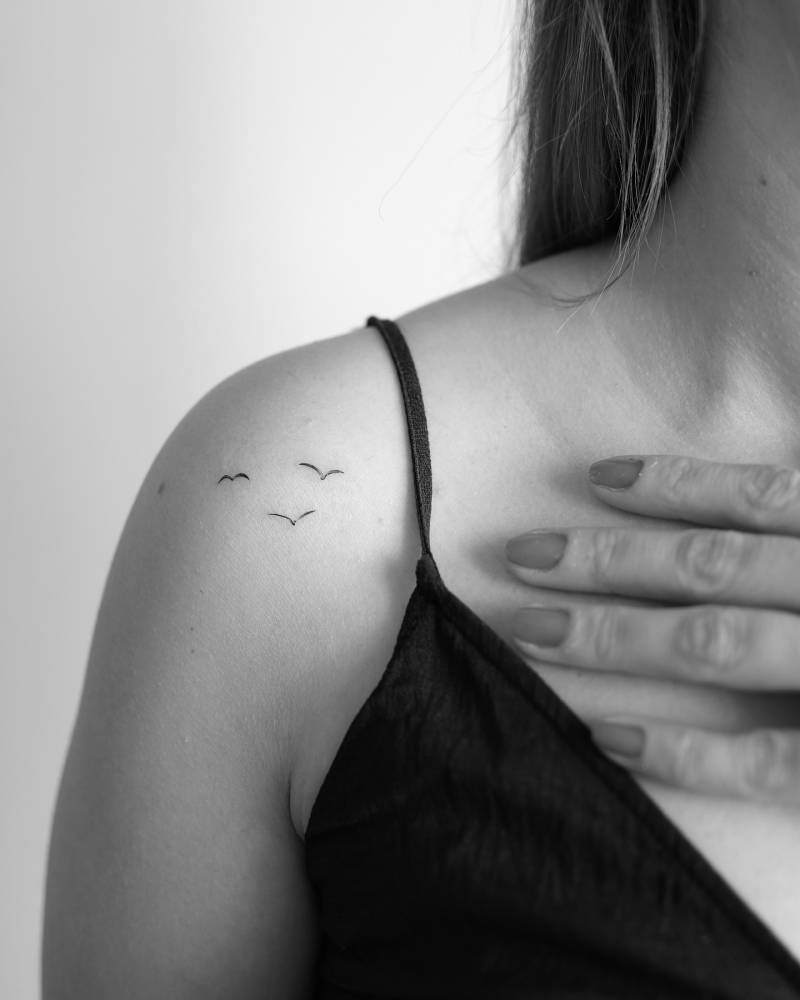 Flying birds tattoo in minimalistic style located on the shoulder.