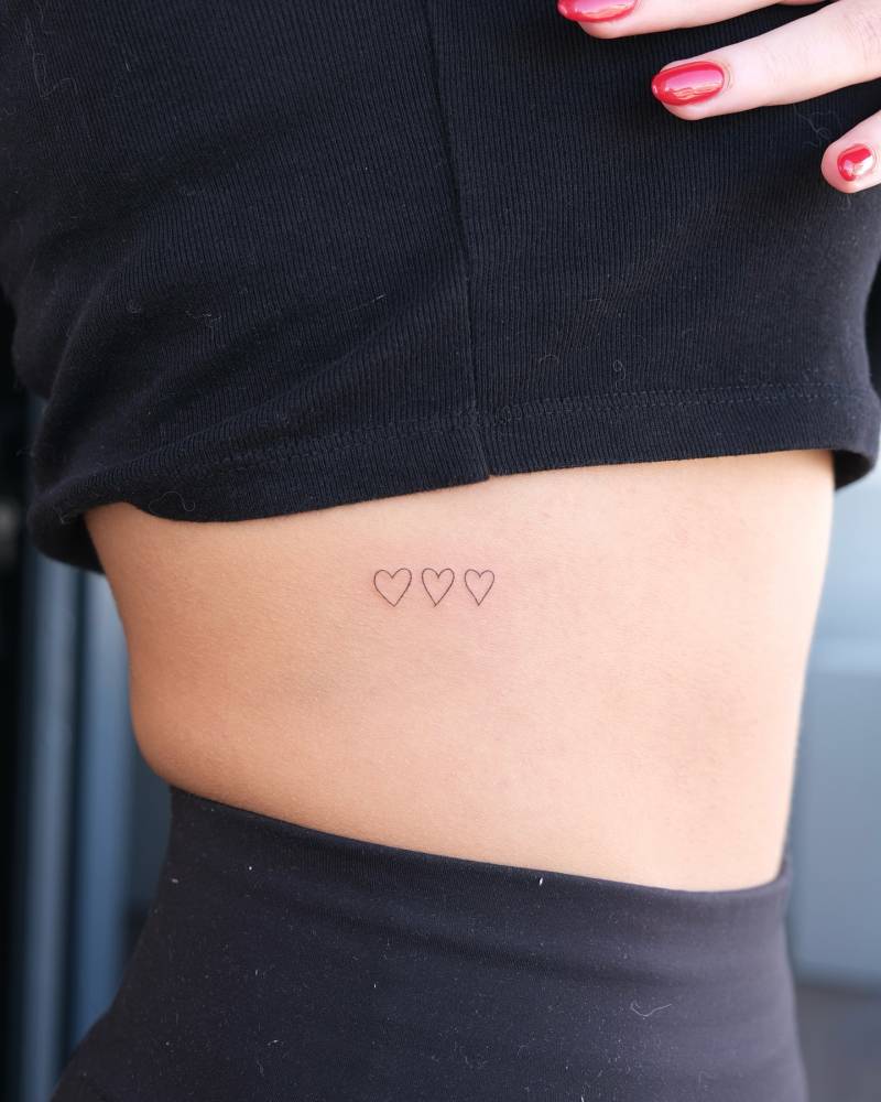 Tiny minimalistic hearts tattooed on the rib.