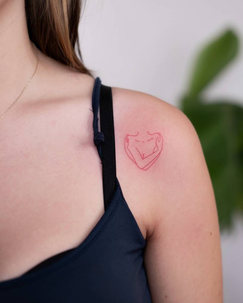 Self hug tattoo in red ink located on the shoulder, fine line style.