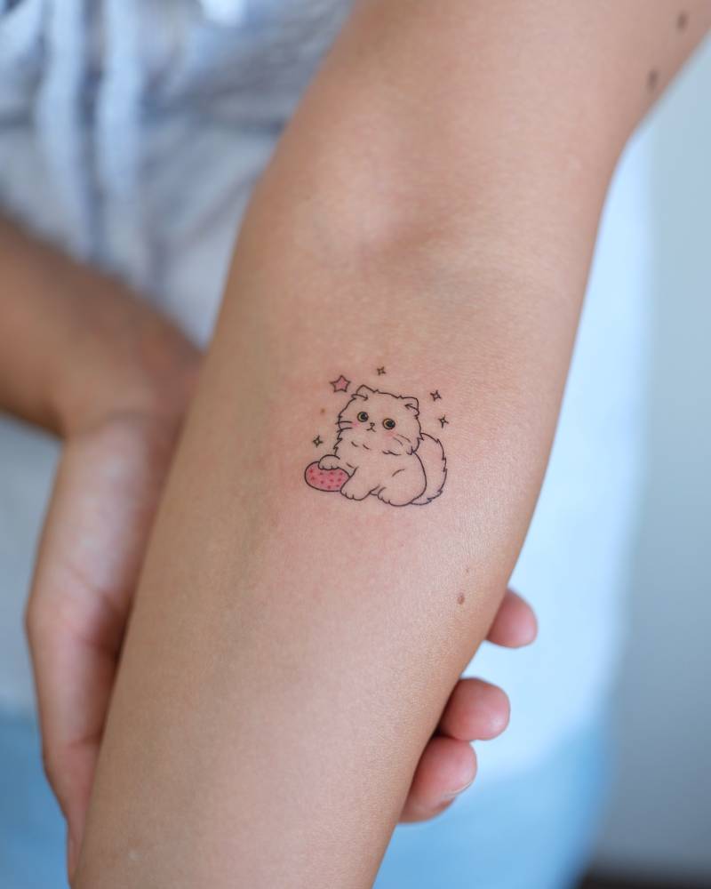 Cartoon style cute cat tattoo located on the inner forearm.