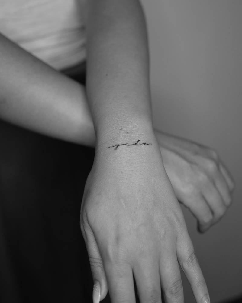 Handwritten name "Yade" tattooed on the wrist.
