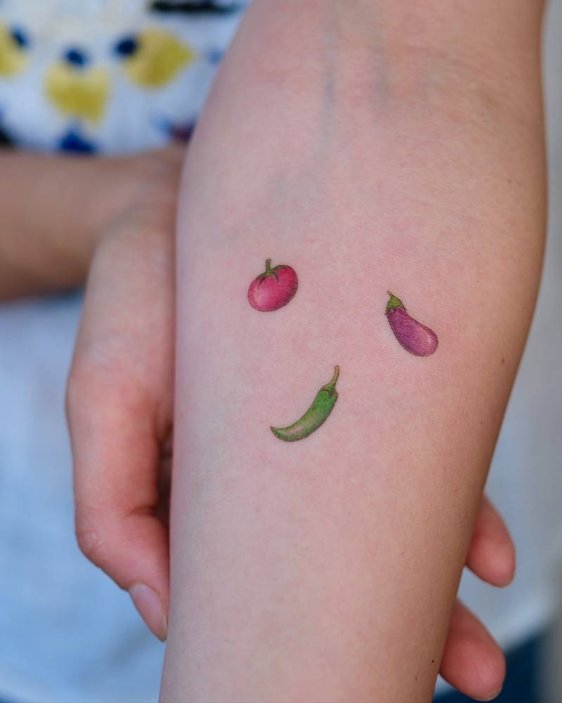 Tomato, eggplant and jalapeno tattoo located on the inner forearm.