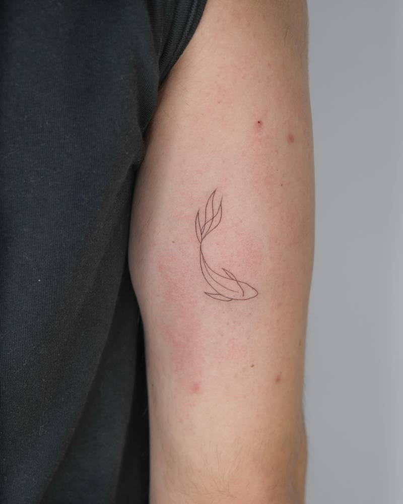 Koi fish tattoo in fine line style placed on the tricep.