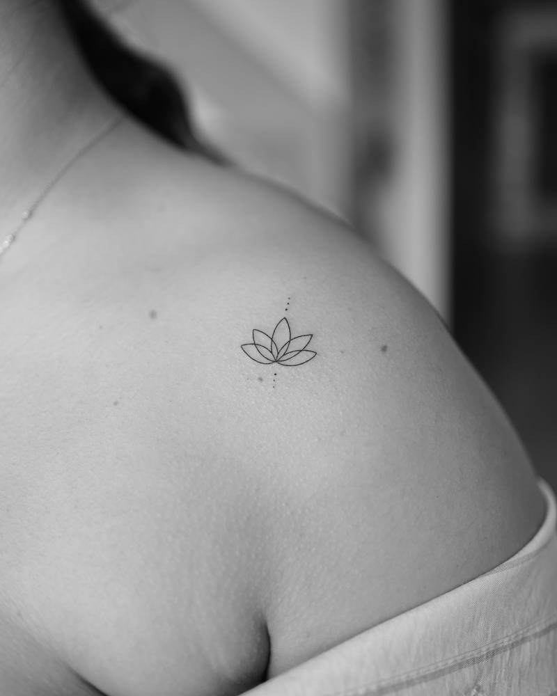 Minimalistic lotus flower tattoo placed on the shoulder.