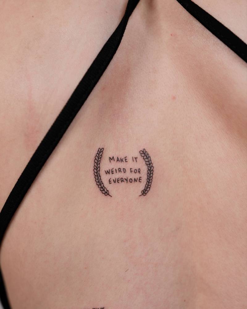"Make it weird for everyone" lettering tattoo located on the back.