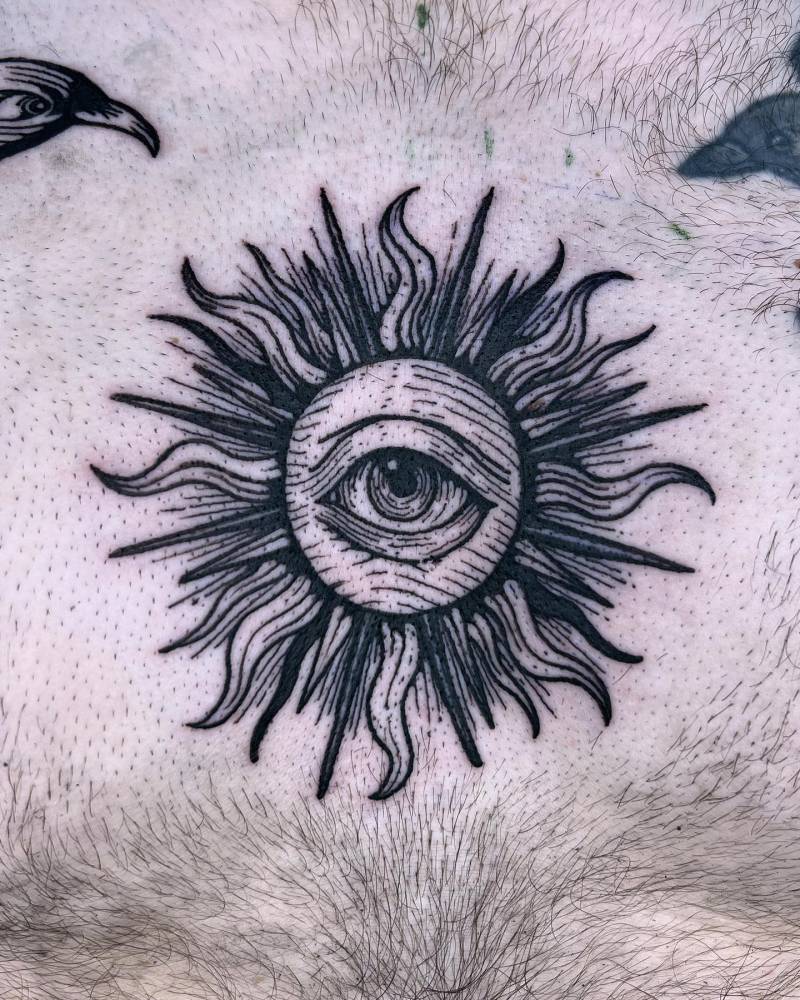 Engraving style sun and eye tattoo placed on the chest.