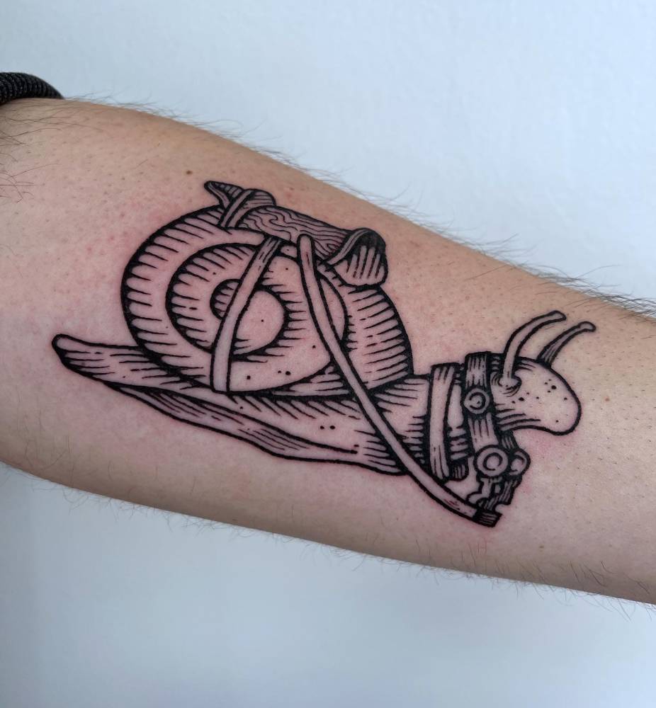 Snail tattoo located on the inner forearm, done in engraving style.